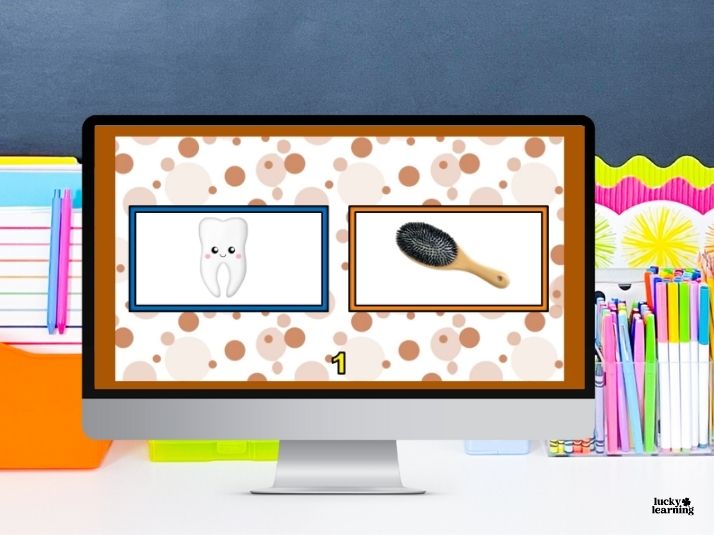 A computer screen displays images of a tooth and a hairbrush side by side, with school supplies in the background—perfect visuals for teaching kids about compound words.