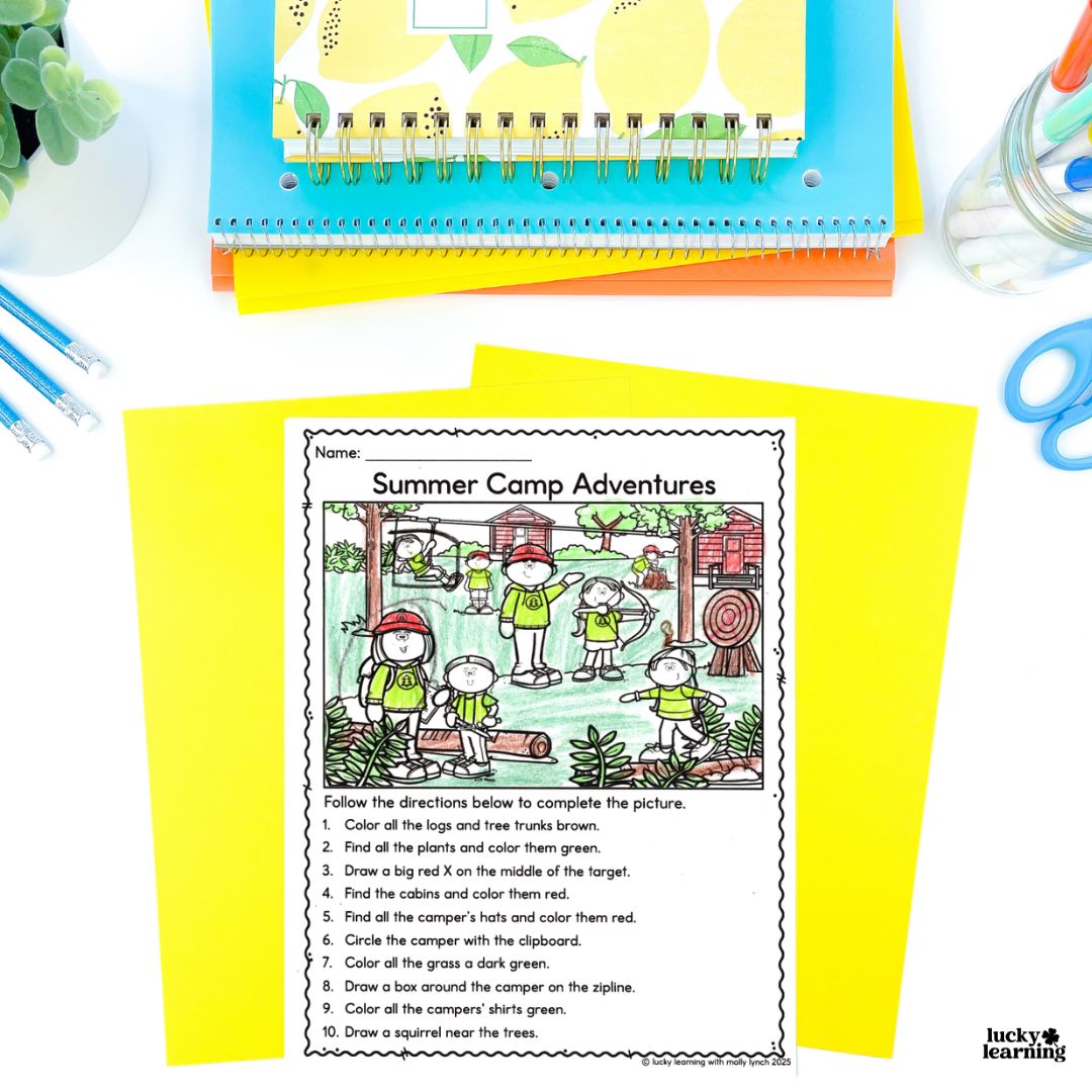 A summer camp-themed worksheet with a coloring and drawing activity focused on following directions is placed on yellow paper, surrounded by school supplies, notebooks, and colored pens.